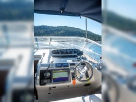 A detailed view of the helm and control console inside a boat, showcasing the navigation equipment and steering wheel, perfect for those interested in boating technology.