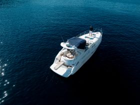 Aerial view of a yacht with a person standing on the deck, showcasing a serene moment on the water — perfect for luxury cruising and relaxation.