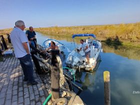 A group of men engage in conversation while a boat is docked nearby, showcasing a moment of camaraderie and interaction in a scenic waterway.