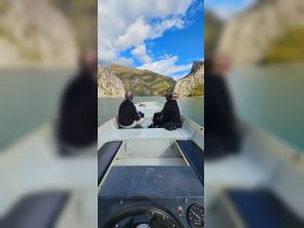 A group enjoys a scenic boat ride through stunning mountain landscapes, perfect for exploring nature's beauty.