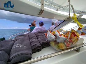 A selection of towels and snacks displayed on a boat, with guests enjoying the view — perfect for a relaxing day on the water.