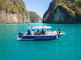 A group enjoys a scenic boat ride through turquoise waters, surrounded by stunning cliffs — perfect for adventure seekers exploring the beauty of nature.