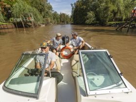 A group of friends enjoys a leisurely boat ride on a river, capturing the essence of adventure and camaraderie on the water.