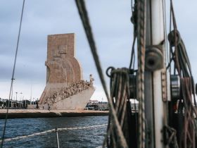 A scenic view of a prominent landmark from a boat, showcasing the intricate details of the monument against a cloudy sky — perfect for capturing the essence of maritime exploration.