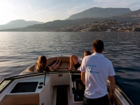 A group enjoys a serene boat ride at sunset, capturing the essence of relaxation on the water amidst stunning mountain views.