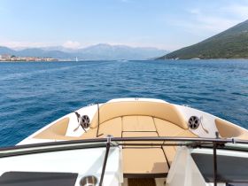 A stunning view from the front of a boat cruising through clear blue waters, showcasing the beautiful landscape and mountains in the background.