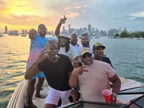 A lively group of friends celebrates on a boat at sunset, enjoying cigars and drinks — perfect for unforgettable summer parties on the water.