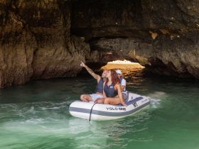 A couple enjoys an adventurous boat ride through a cave, pointing out the stunning scenery — a perfect highlight of their exploration on the water.