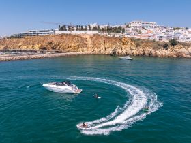 A thrilling scene of water sports with a group enjoying jet skiing and paddleboarding against a picturesque coastal backdrop — perfect for adventure seekers.