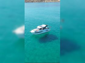 A scenic view of a boat anchored in crystal-clear turquoise waters, with swimmers enjoying the refreshing sea — a perfect setting for a summer adventure.