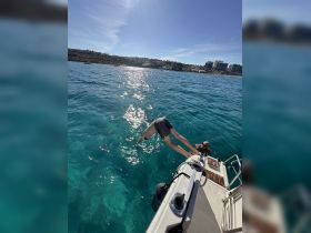 Two individuals enjoy a thrilling moment as one jumps into the crystal-clear waters from the boat, capturing the essence of summer fun on the water.