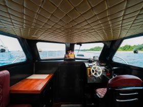 Interior view of a boat's helm and cabin area, showcasing the steering console and comfortable seating — ideal for navigating the waters in style.