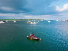Aerial view of a sleek boat anchored in a serene harbor, surrounded by various other vessels — a perfect scene for boating enthusiasts and coastal adventures.