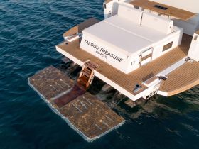 A stunning aerial view of the 'Yalou Treasure' yacht docked, showcasing its elegant design and spacious rear deck, perfect for relaxation on the water.