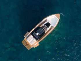 Aerial view of a sleek boat equipped with solar panels, gliding over clear blue waters — perfect for eco-friendly adventures on the sea.