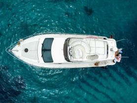 Aerial view of a boat with guests enjoying the clear waters, showcasing a fun day on the water with swimming and relaxation.