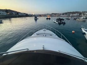 A stunning view from the front of a yacht docked in a serene harbor, showcasing the tranquil waters and surrounding coastal scenery.