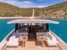 An elegant interior view of a yacht's dining area, featuring a beautifully set table with refreshments, perfect for luxurious onboard dining experiences.