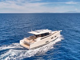 A stunning aerial view of a sleek yacht cruising through deep blue waters, showcasing its modern design and spacious deck — perfect for luxury charters and ocean adventures.