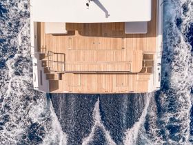Aerial view of a sleek boat's deck, showcasing its elegant wooden flooring as it glides through the water — perfect for luxury cruising experiences.