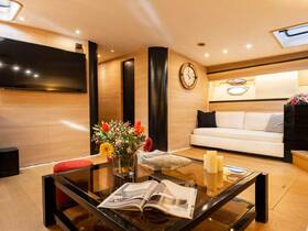 A stylish and modern interior of a boat cabin featuring comfortable seating, a coffee table, and decorative elements, perfect for relaxing on the water.
