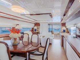 An elegant interior view of a yacht's cabin featuring a dining area and comfortable seating, perfect for relaxing and enjoying the scenic ocean views.