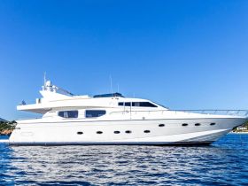 A stunning side view of a luxurious yacht docked in calm waters, showcasing its elegant design against a clear blue sky.