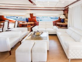 A beautifully designed interior of a yacht featuring elegant white seating and a spacious lounge area, perfect for relaxation while enjoying views of the water.