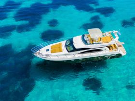 A stunning aerial view of a luxurious yacht gliding over crystal-clear turquoise waters, perfect for upscale charters and leisurely cruises.