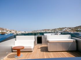 A stylish interior view of a yacht's deck featuring comfortable seating and a modern helm, perfect for relaxing while enjoying scenic coastal views.