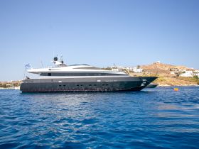 A stunning side view of a luxurious yacht docked in clear blue waters, showcasing its elegant design against a picturesque coastal backdrop.