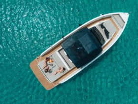 Aerial view of friends enjoying a relaxing day on a boat, sunbathing and sharing a delicious spread of food — the perfect setting for a summer getaway.
