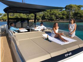A lively group enjoys a sunny day on a yacht, celebrating with drinks and relaxation on the deck — perfect for summer outings and gatherings.