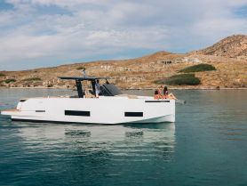 A couple enjoys a relaxing moment on the edge of a sleek boat, surrounded by serene waters and picturesque island scenery — perfect for a day of adventure and leisure.