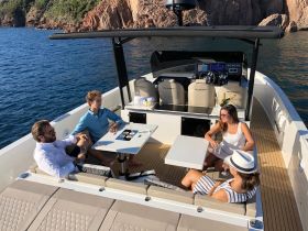 A lively group enjoys drinks and conversation on the deck of a stylish boat, perfect for celebrating special moments on the water.