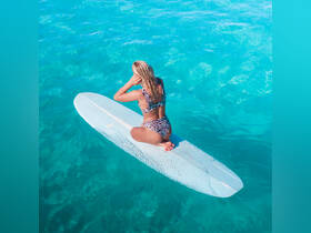 A woman enjoys paddleboarding in crystal-clear waters, showcasing the perfect blend of adventure and relaxation in a tropical paradise.