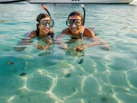 A joyful couple enjoys snorkeling in crystal-clear waters, surrounded by colorful fish — a perfect moment for underwater exploration and adventure.
