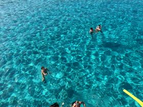 A group enjoys a refreshing swim in crystal-clear waters, showcasing the perfect setting for a fun day on the water.