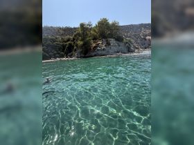 A serene view of crystal-clear waters with a swimmer enjoying the beautiful coastline — perfect for a relaxing day on the water.