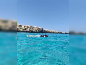 A child enjoys snorkeling in crystal-clear waters near rocky formations, showcasing the beauty of underwater adventures and marine exploration.