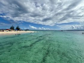 A picturesque view of a beach with people swimming in crystal-clear turquoise waters, showcasing the beauty of a tropical island getaway.