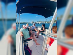 A lively group enjoys their time aboard a boat, sharing drinks and laughter against a picturesque marina backdrop — perfect for social gatherings and celebrations on the water.