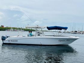 A boat named 'Captain Tony' is underway with two individuals on board, showcasing a vibrant day on the water in Isla Mujeres.