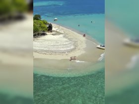 A group of friends enjoys a sunny day at a picturesque sandbar, capturing memories in the shallow waters — an ideal spot for beach fun and relaxation.