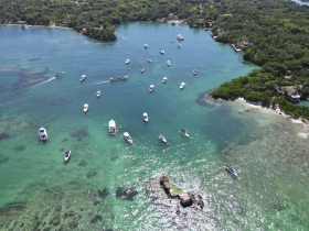 A stunning aerial view of a vibrant bay filled with various boats, showcasing the beautiful turquoise waters and lush coastline — perfect for exploring and enjoying water activities.