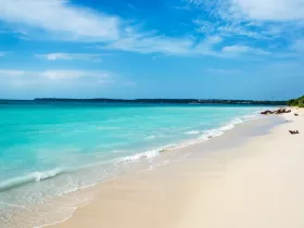 A stunning view of a serene beach with turquoise waters and soft sand, perfect for relaxation and enjoying the natural beauty of the coastline.