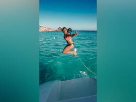 A joyful moment captured as a woman leaps into the vibrant turquoise waters, showcasing the excitement of summer water activities.