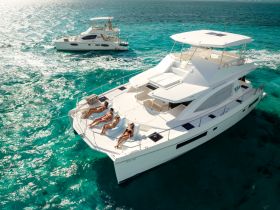 A group of friends relaxes on the deck of a luxurious yacht, soaking up the sun in stunning turquoise waters — an ideal setting for a day of leisure on the sea.