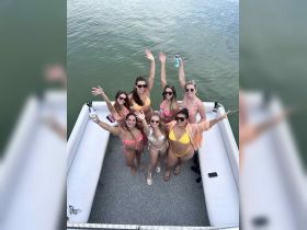 A lively group of friends celebrates on a pontoon boat, enjoying drinks and sunshine — perfect for summer parties and fun on the water.