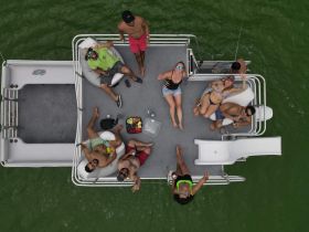 A lively group enjoys a fun day on a pontoon boat, relaxing with drinks and snacks while soaking up the sun on the water.